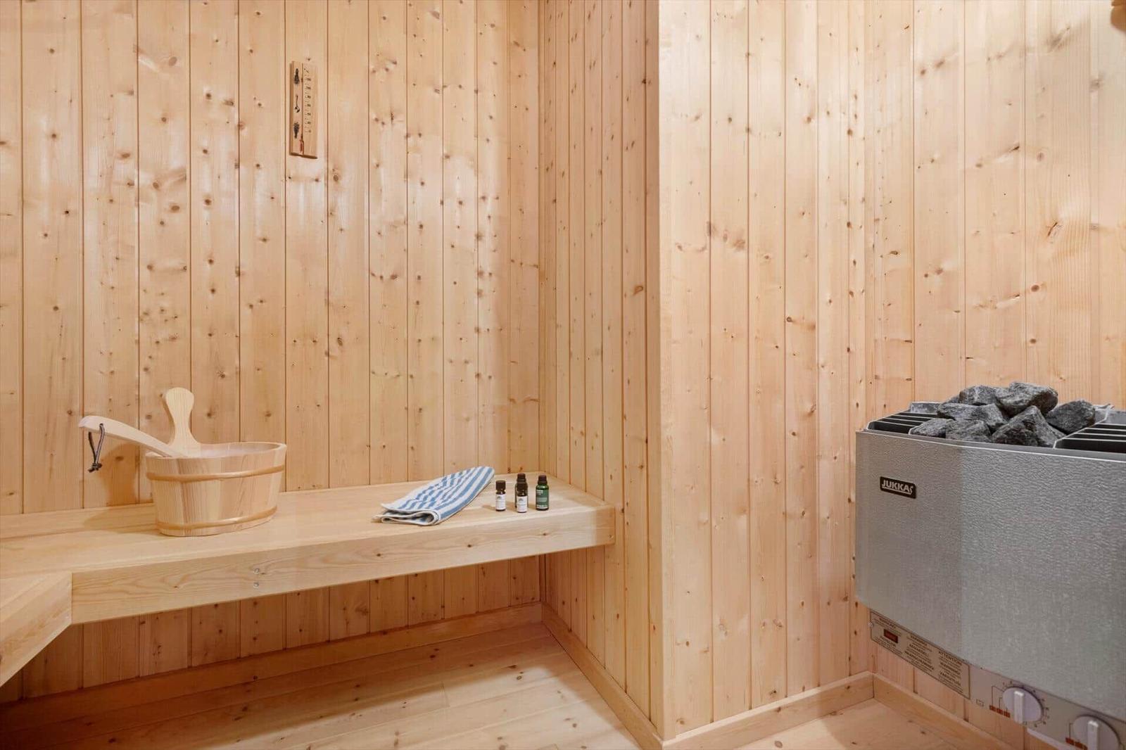 Sauna with wooden walls, bench, bucket, towel, and stones.