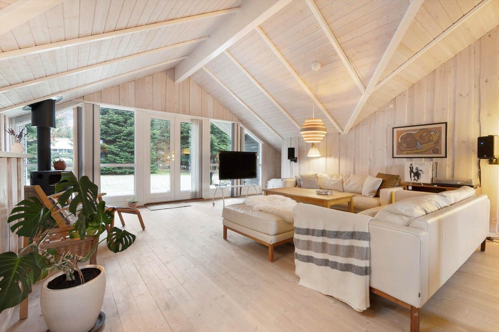 Living room with wooden walls, sofa, TV, and large windows.