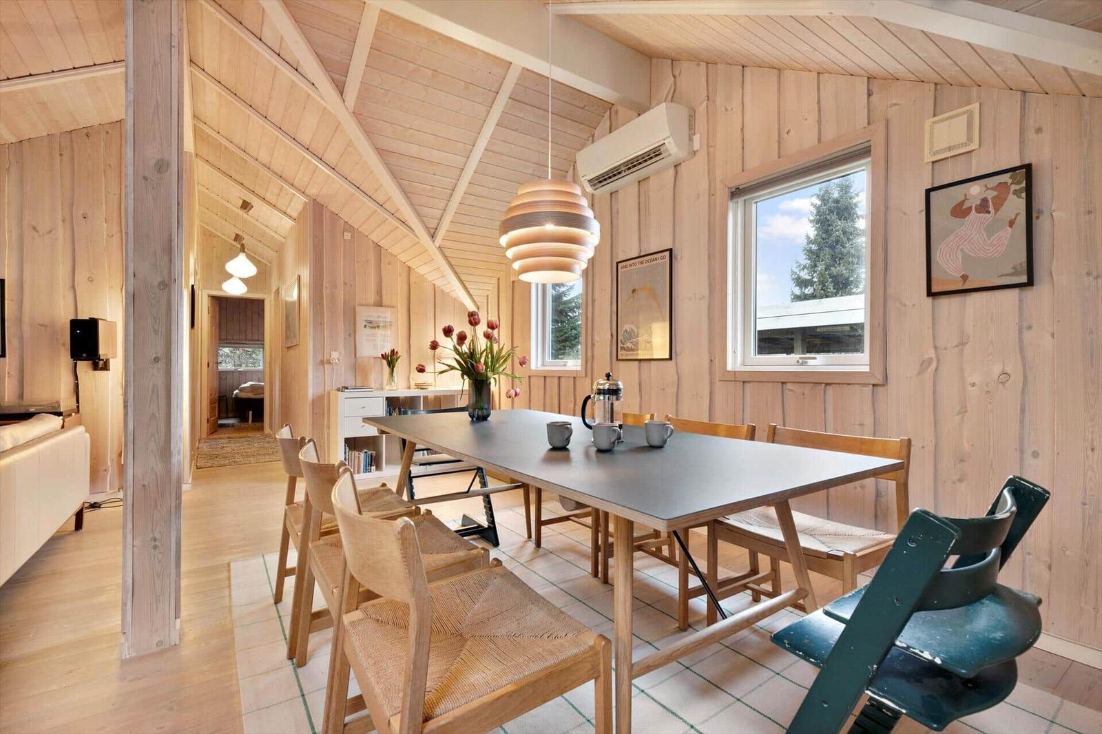Dining room with wooden walls, table, chairs, window, and ceiling light.
