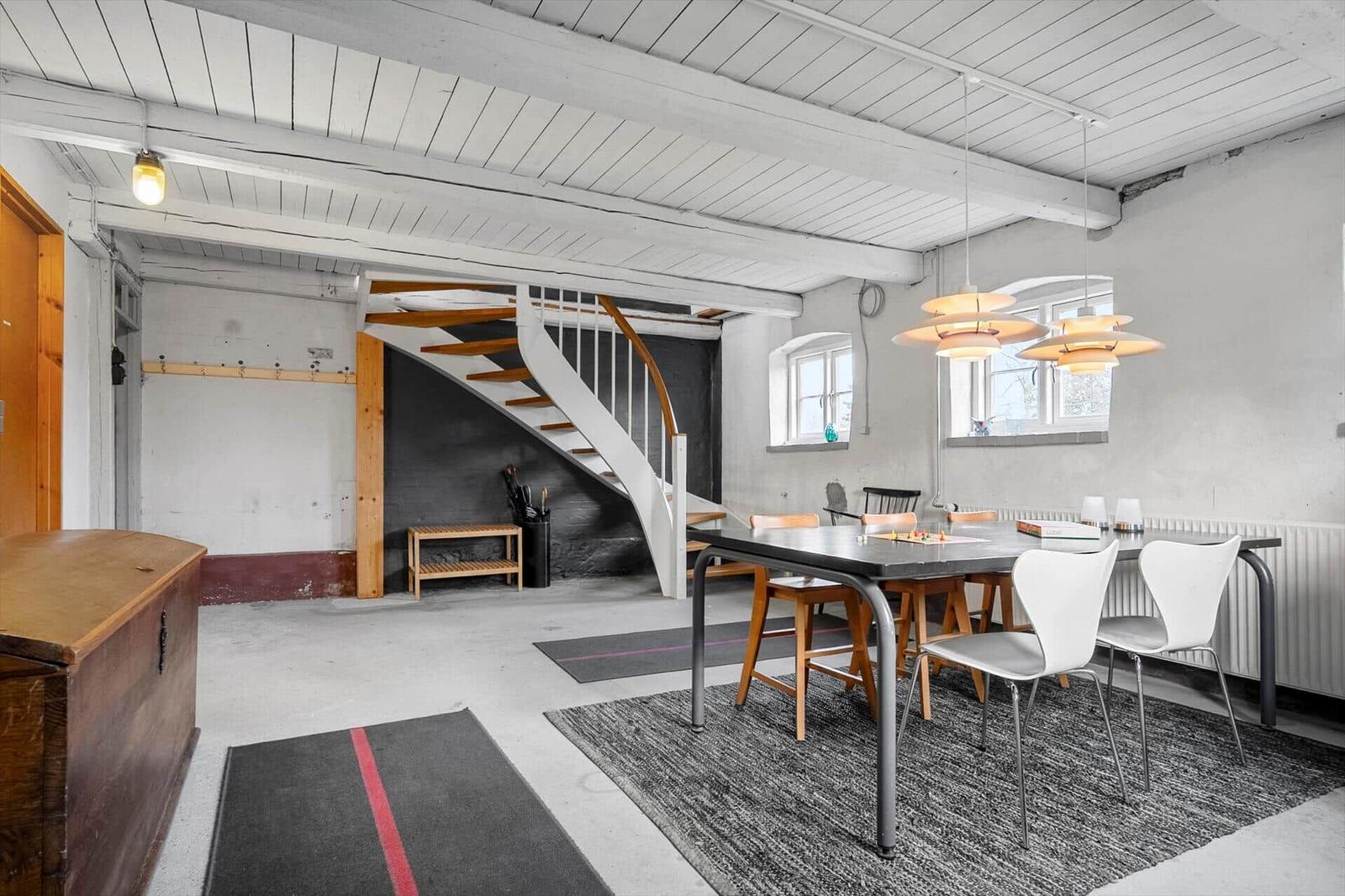 Esszimmer mit Tisch, Stühlen und Wendeltreppe. Decke mit Balken und Fenster.