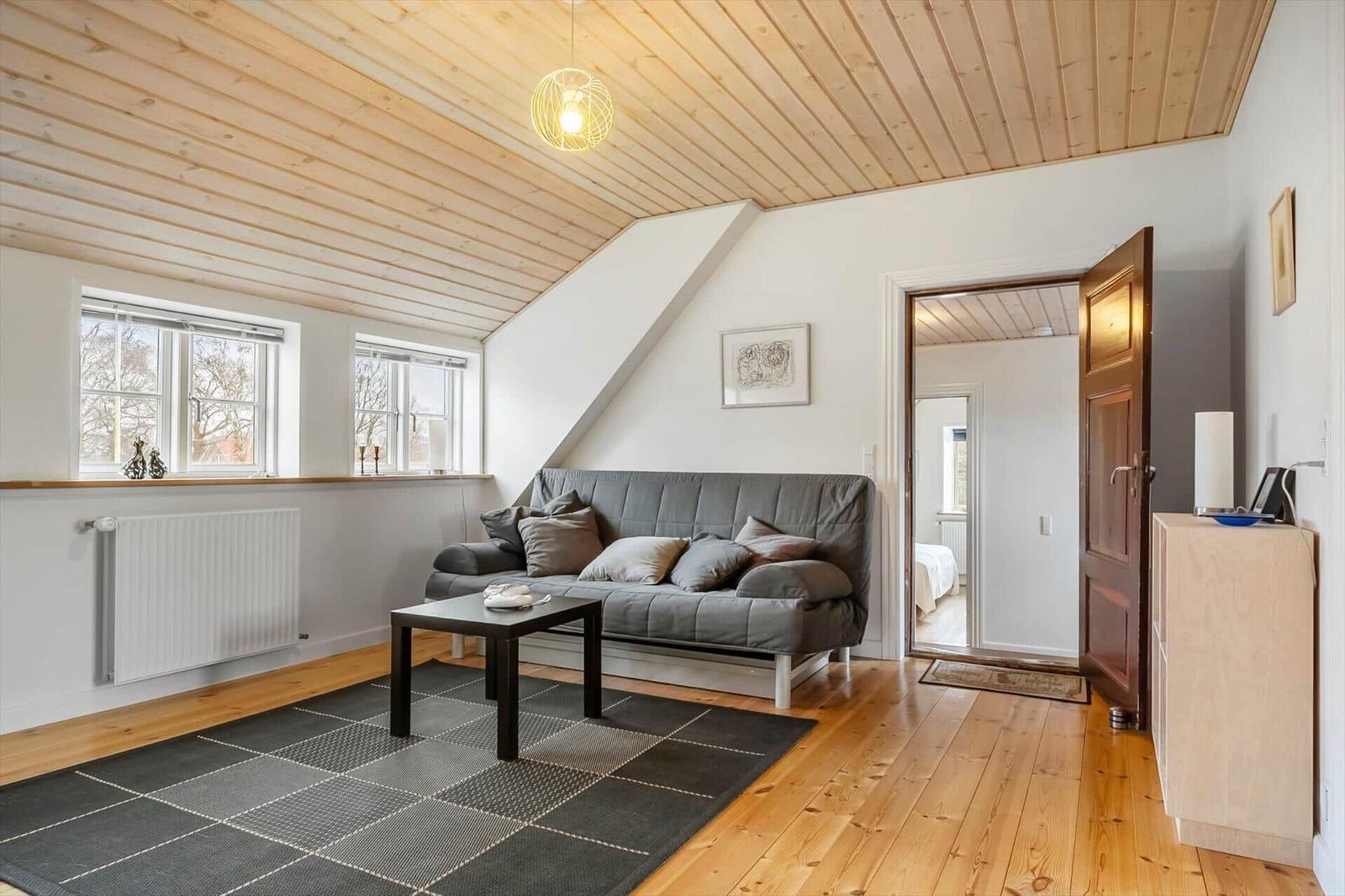 Wohnraum mit Sofa, Tisch und Holzboden unter Holzdecke