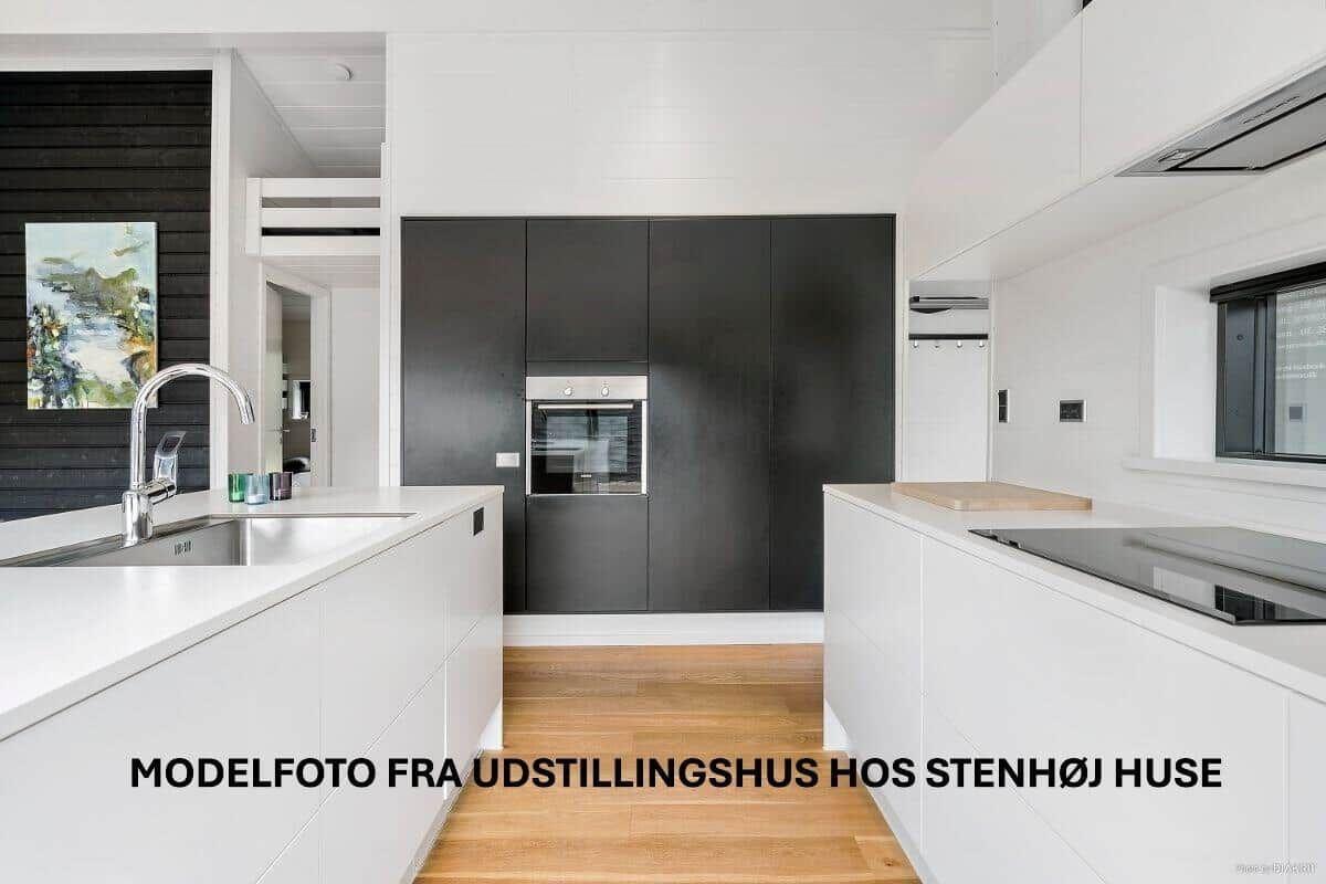 Modern kitchen with white countertops and black cabinets. Wooden floor and built-in oven.