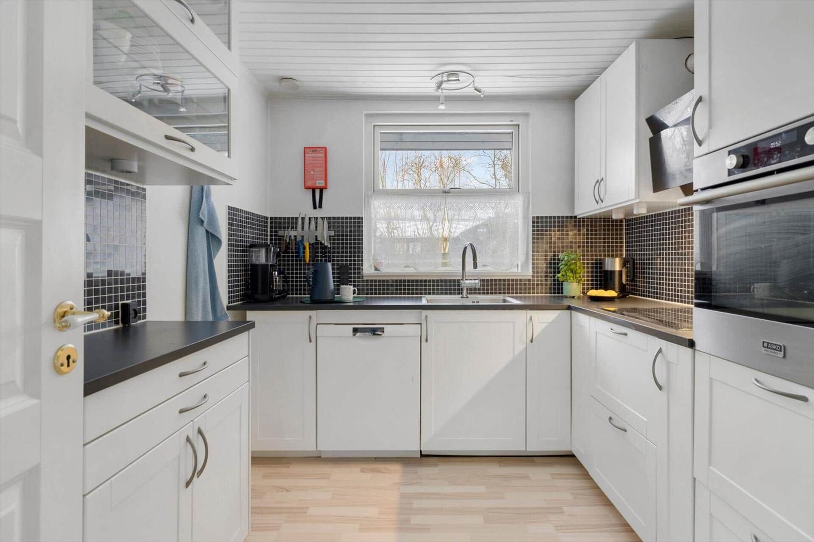 Kitchen with white cabinets, dark countertops, and window with view outside.