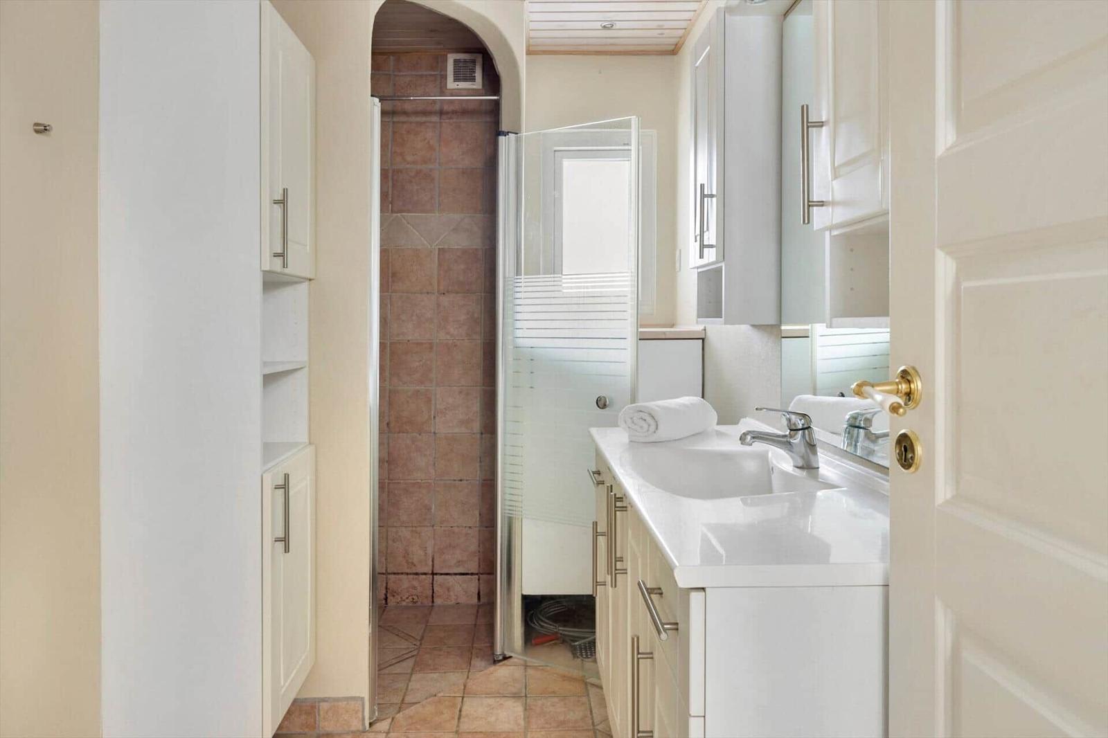 Bathroom with shower, sink, and cabinets.