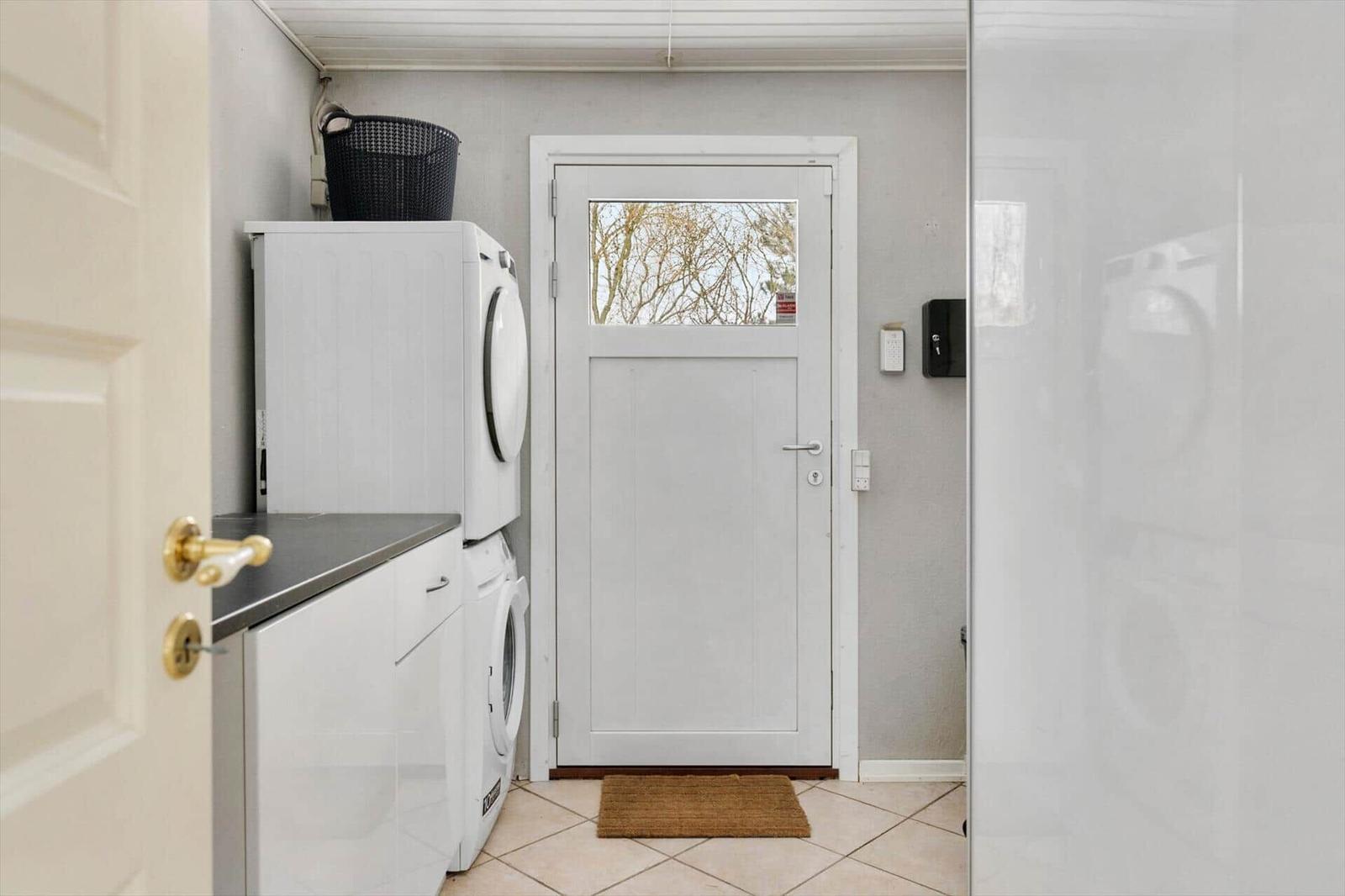 Entrance with washer and dryer, door with glass panel and doormat.