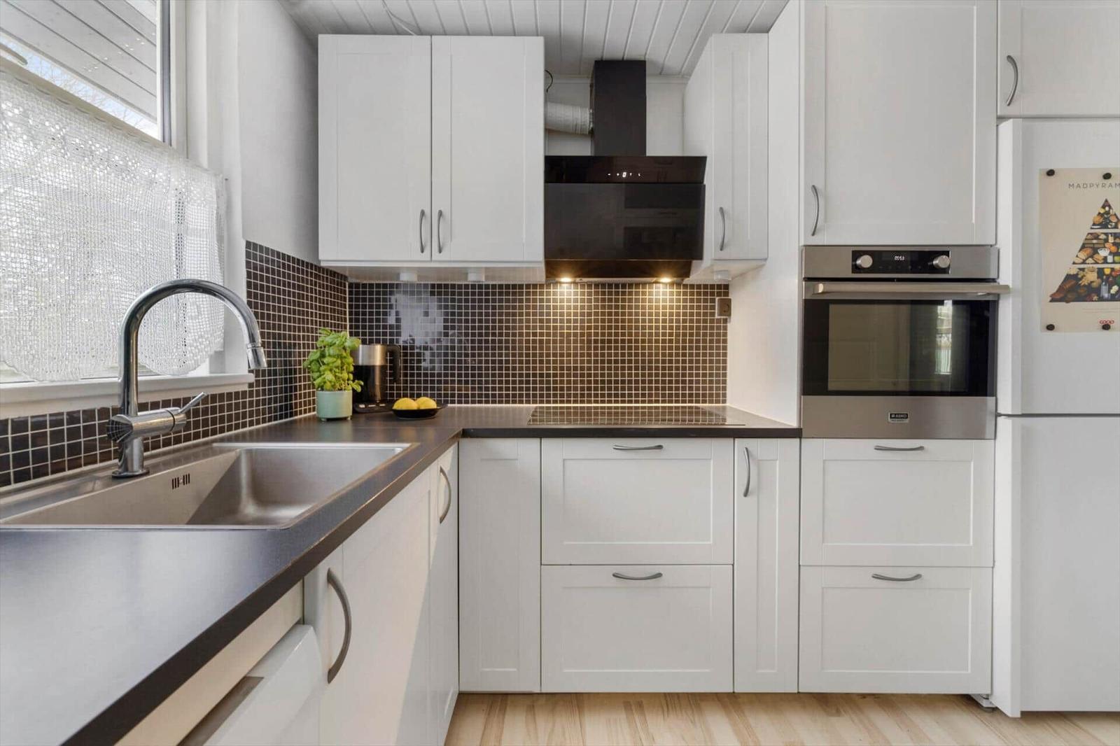 Kitchen with white cabinets, dark countertop, and oven.
