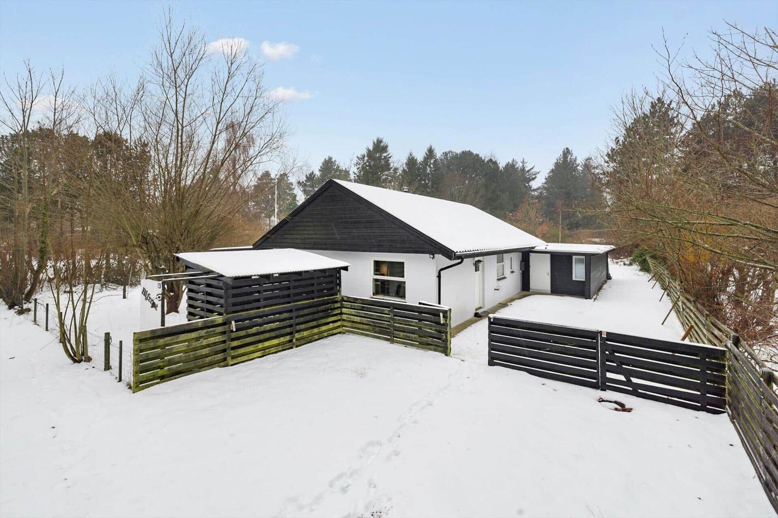 House with snow-covered roof and wooden railing in winter.