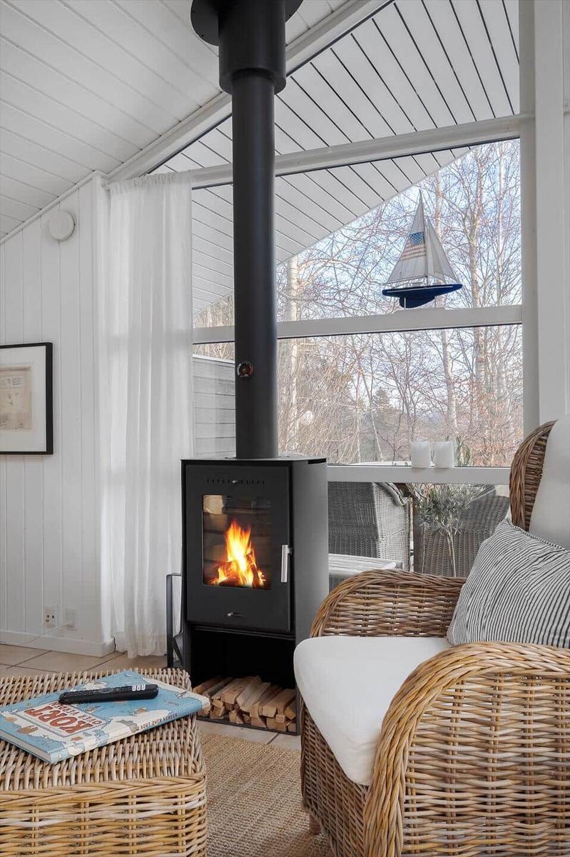Living area with wood stove, wicker furniture, and view to outside.