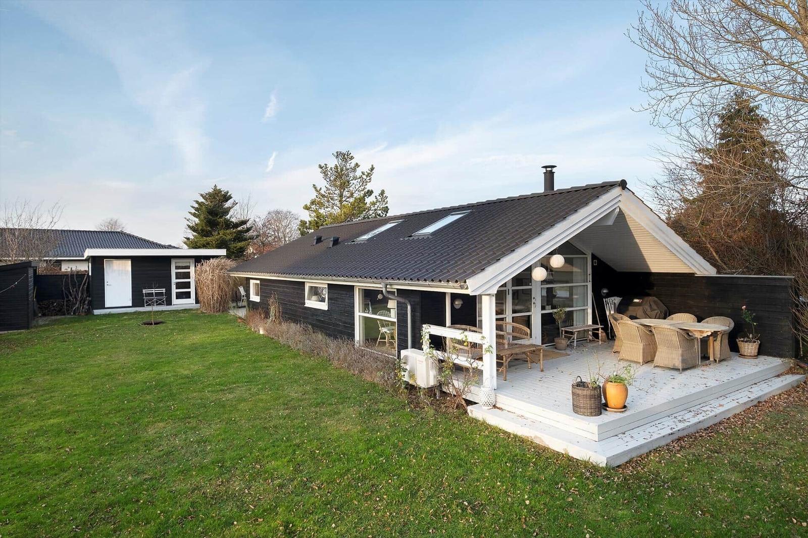 House with terrace, garden, and seating. Black facade, white veranda.