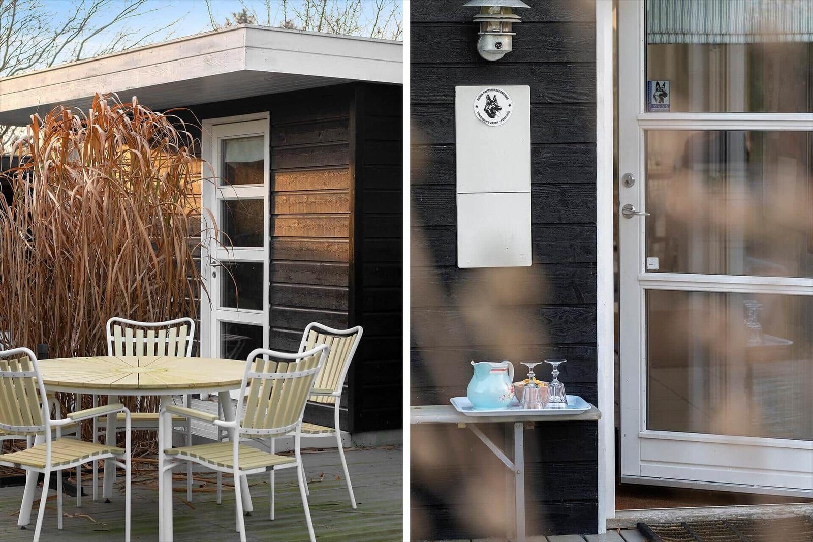 House with terrace, table and chairs. Door with drink tray and dog sign.