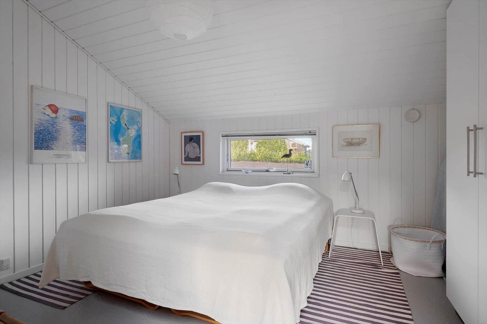 Bedroom with white bed, window, and wall art.