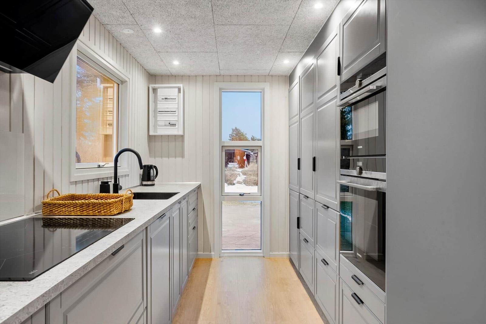Modern kitchen with gray cabinets, countertop, and window view.