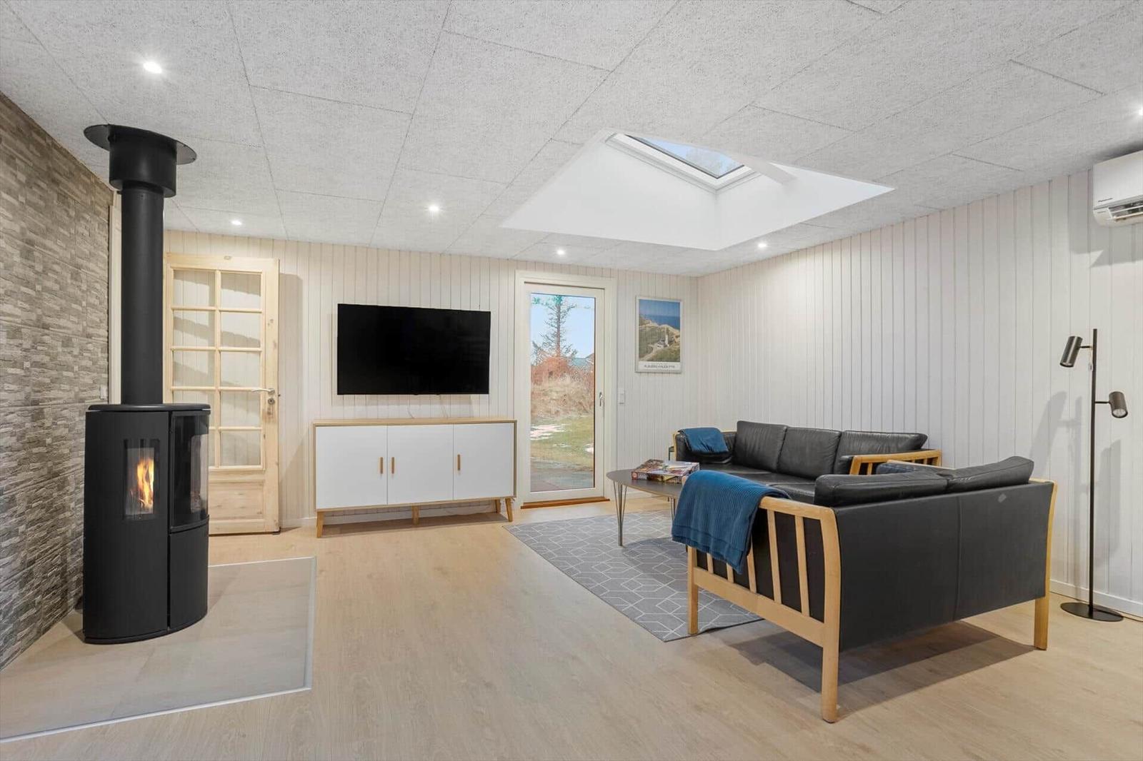 Living room with sofa, TV, and wood-burning stove. Window to the outside.