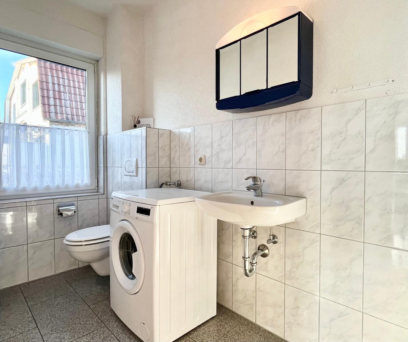 Badezimmer mit Waschbecken, Wc und Waschmachine
