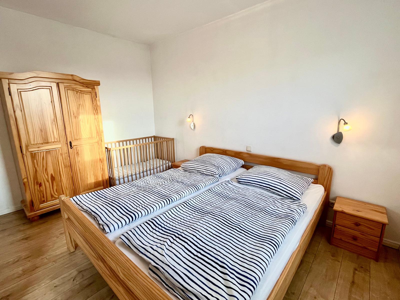 Schlafzimmer mit Ehebett Blick auf Kleiderschrank und Babybett