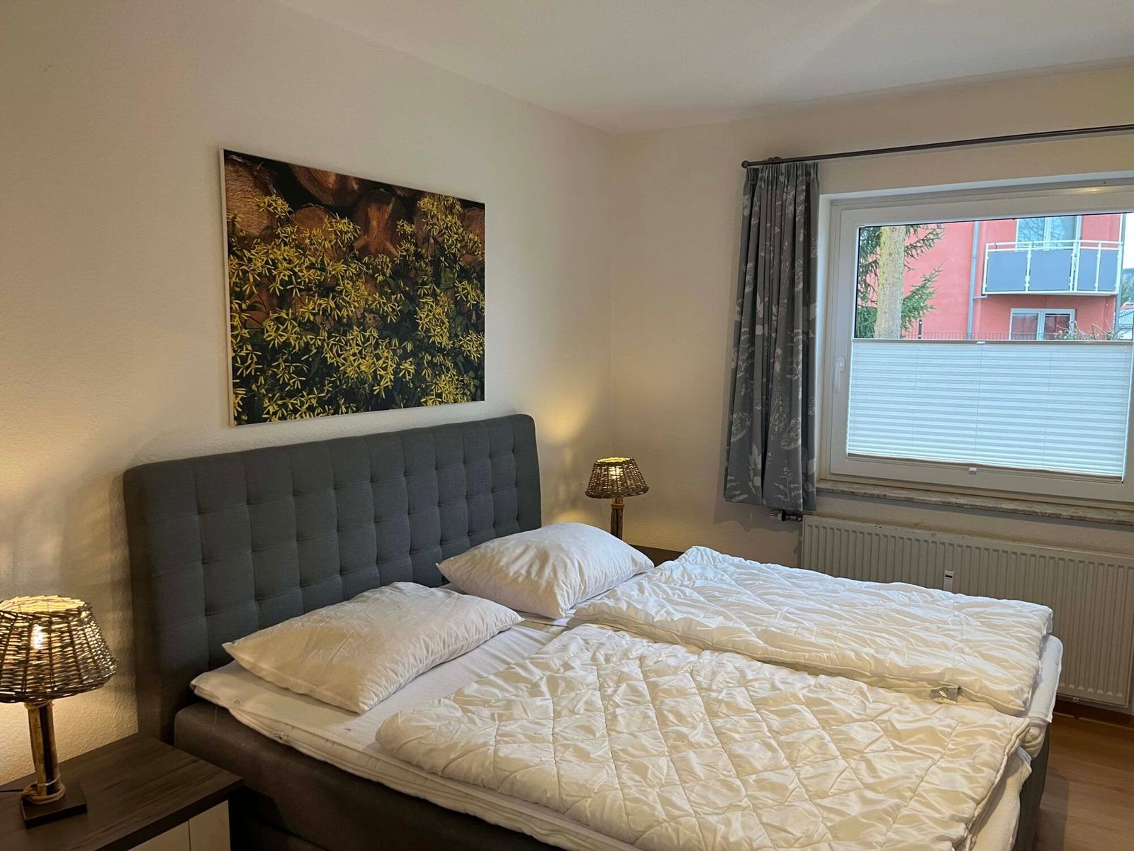 Schlafzimmer mit Doppelbett, Wandbild und Fenster mit Blick.