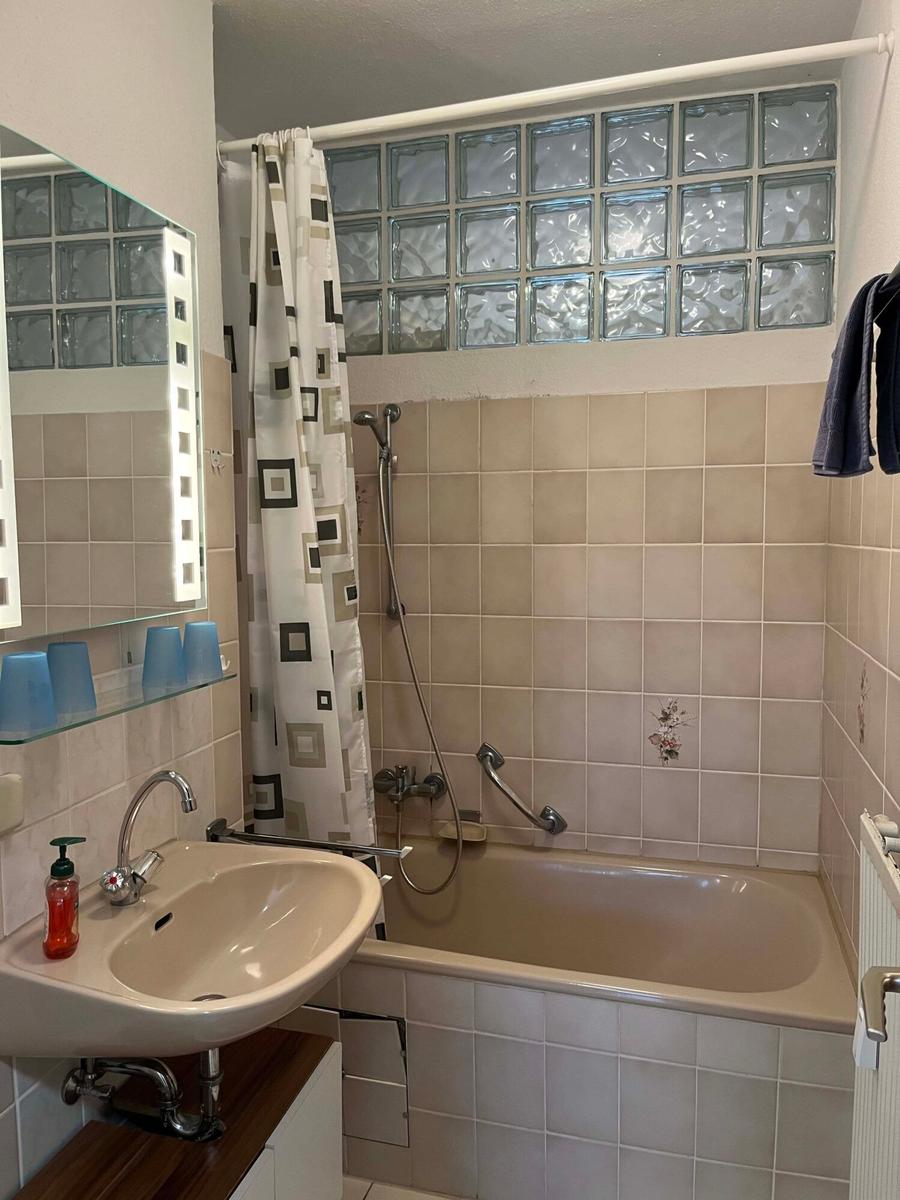 Badezimmer mit Badewanne, Duschvorhang und Spiegel