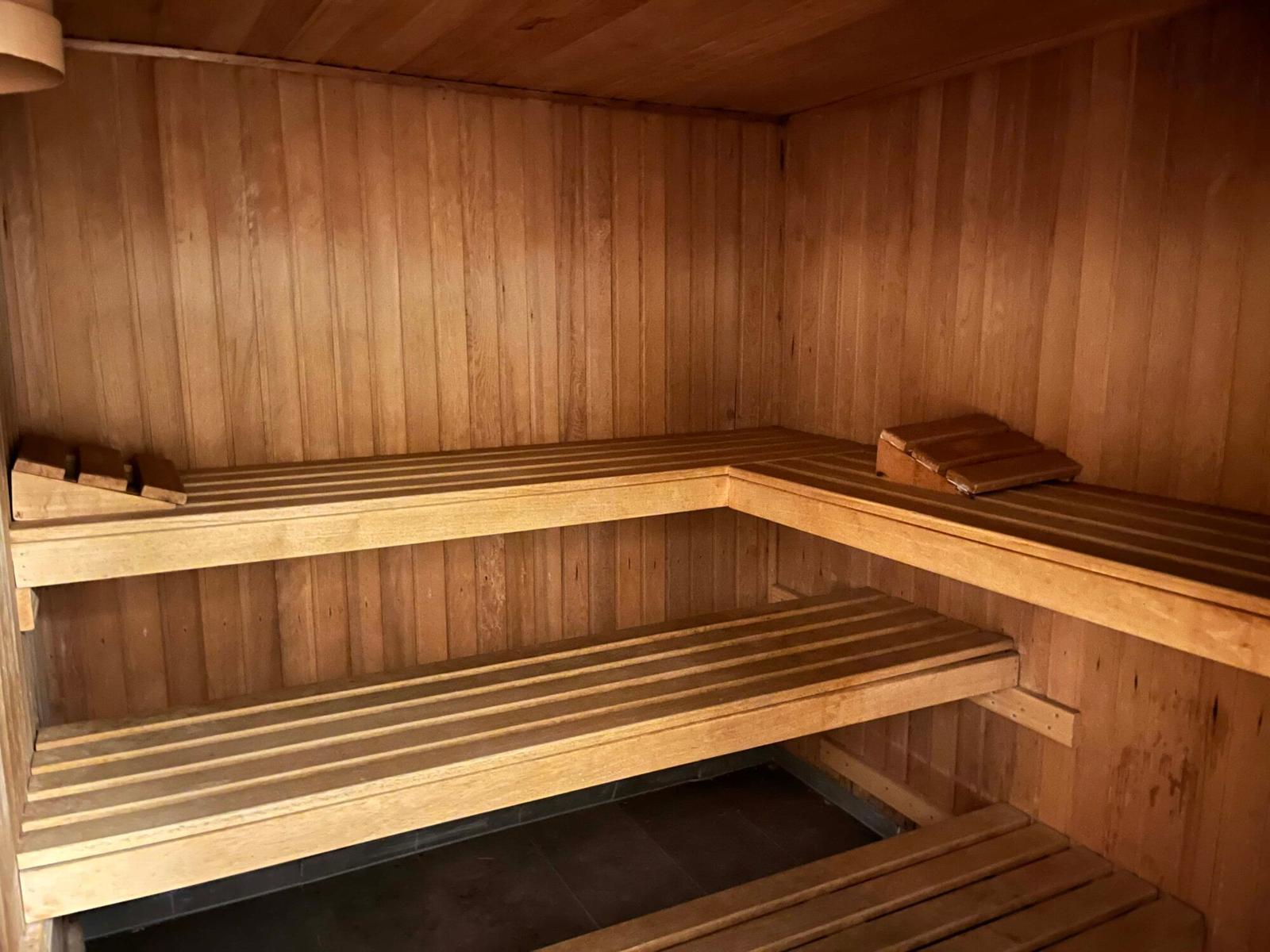 Holzsauna mit mehreren Sitzbänken und Holzverkleidung an den Wänden.