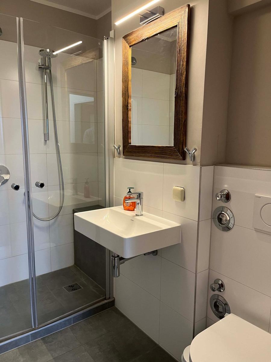 Badezimmer mit Dusche, Waschbecken und Spiegel.