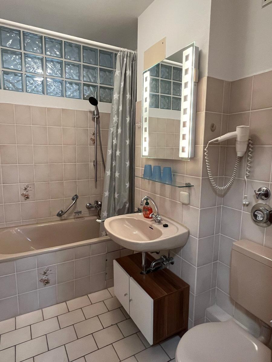 Badezimmer mit Badewanne, Spiegel und Toilette.