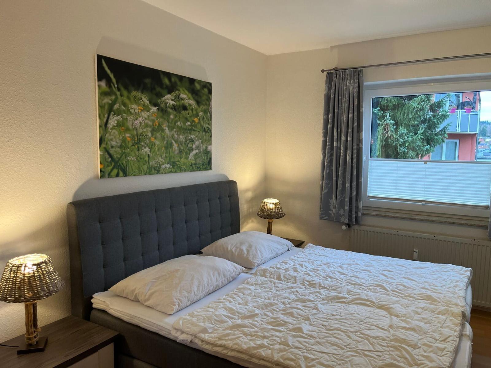 Schlafzimmer mit Bett, Nachttischen und Fenster