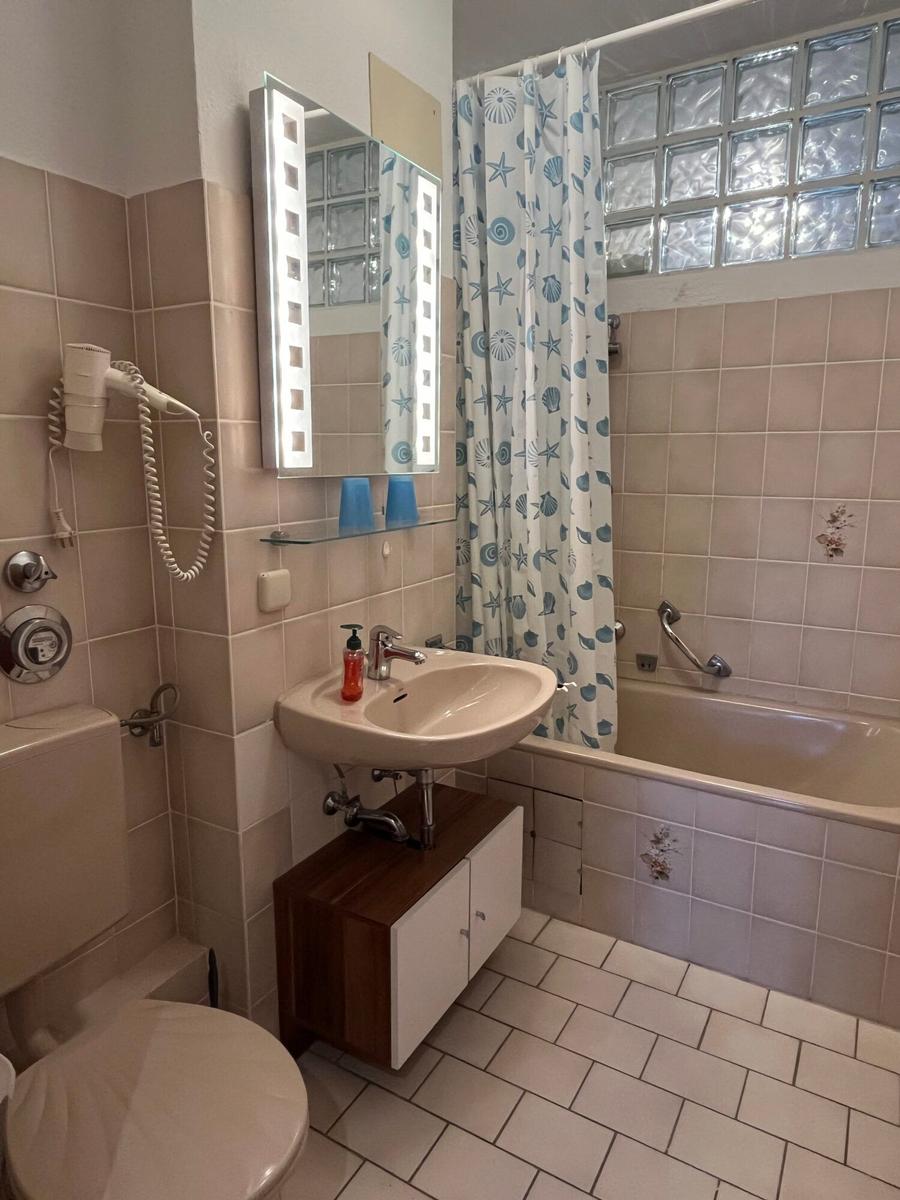 Badezimmer mit Badewanne, Spiegel und Toilette.