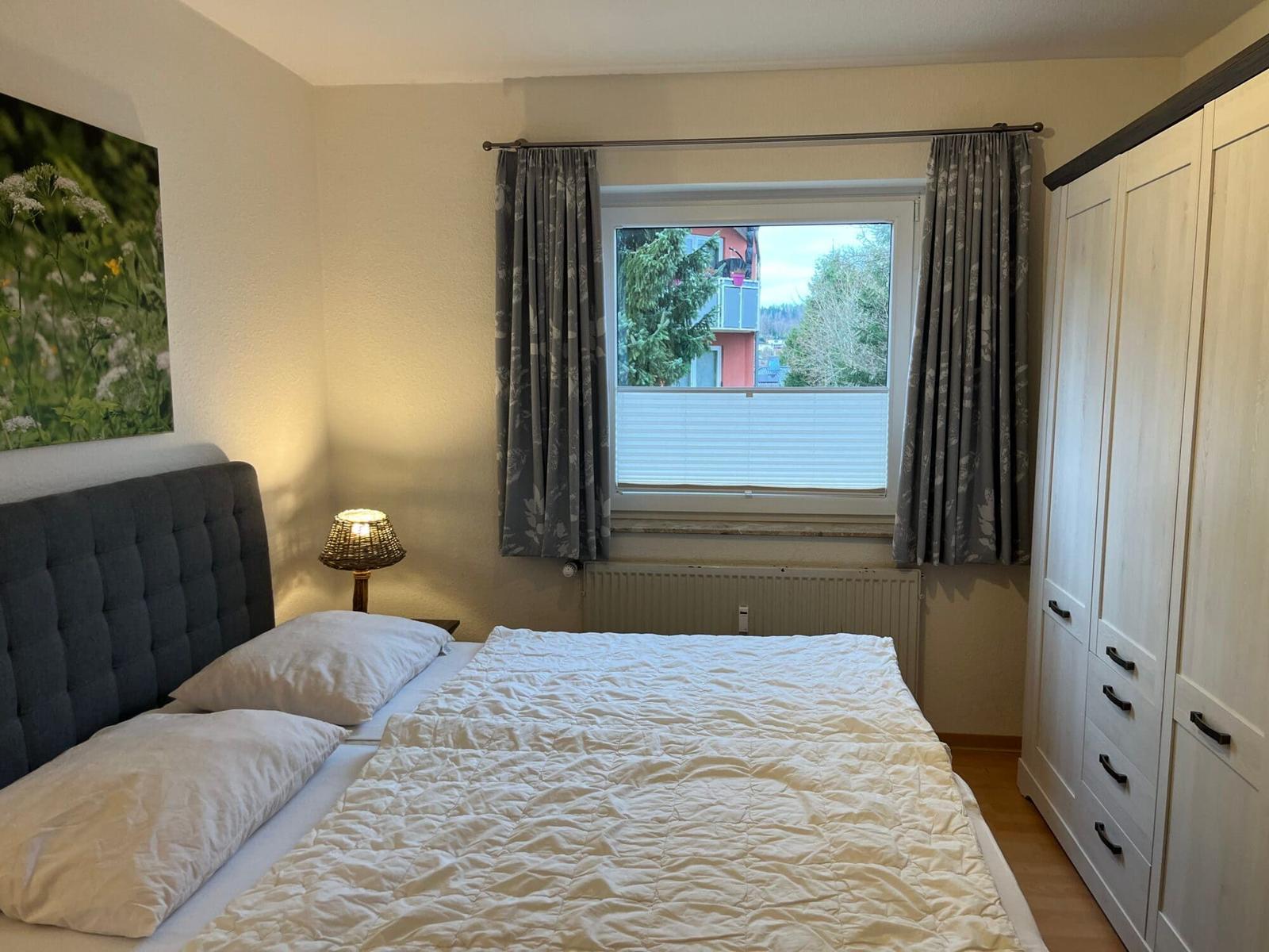 Schlafzimmer mit Bett, Kleiderschrank und Fenster mit Blick.