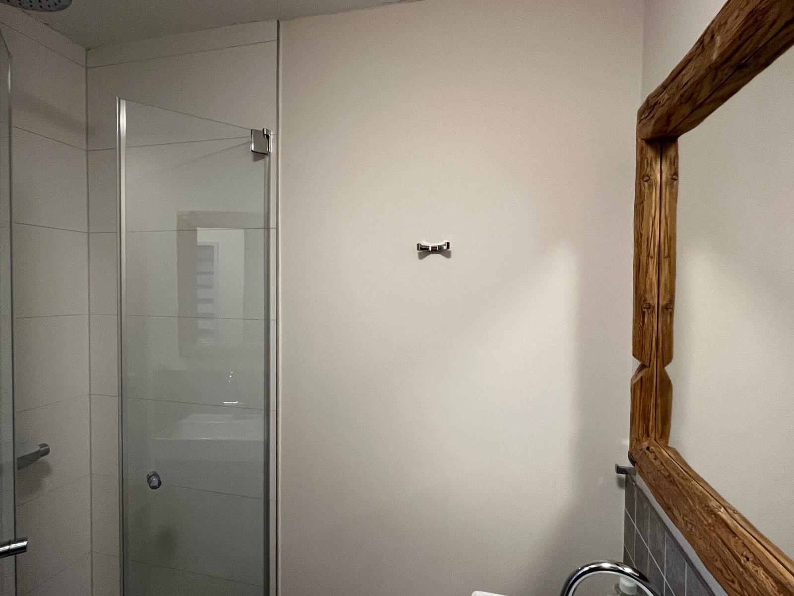 Badezimmer mit Dusche und Holzspiegelrahmen