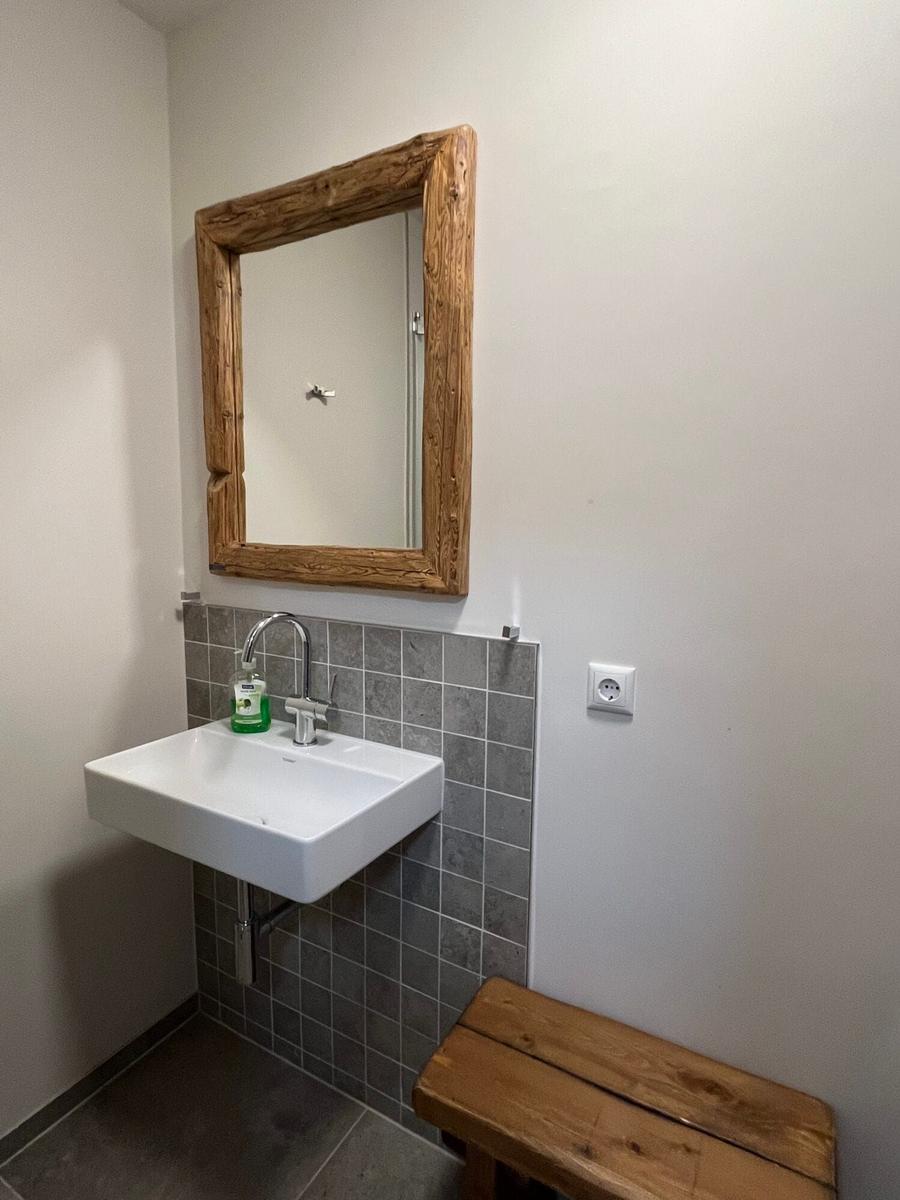 Badezimmer mit Waschbecken, Spiegel und Holzbank.