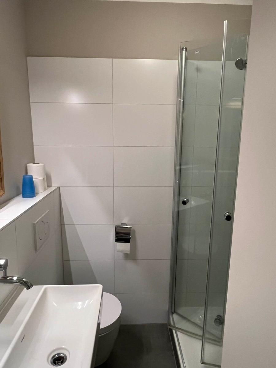 Badezimmer mit Dusche, Waschbecken und Toilette.