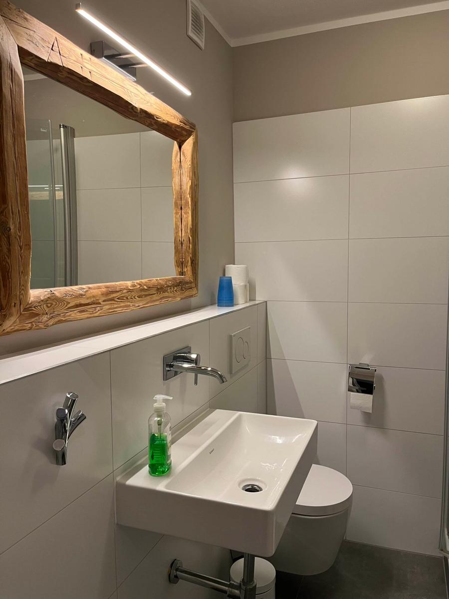 Bad mit Waschbecken, Toilette und Spiegel mit Holzrahmen