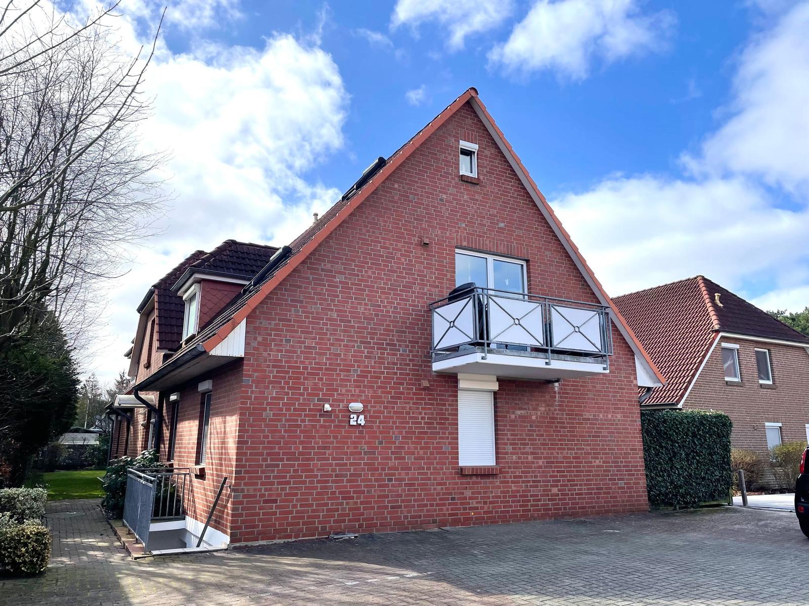 Red brick building with balcony and terrace under blue sky.