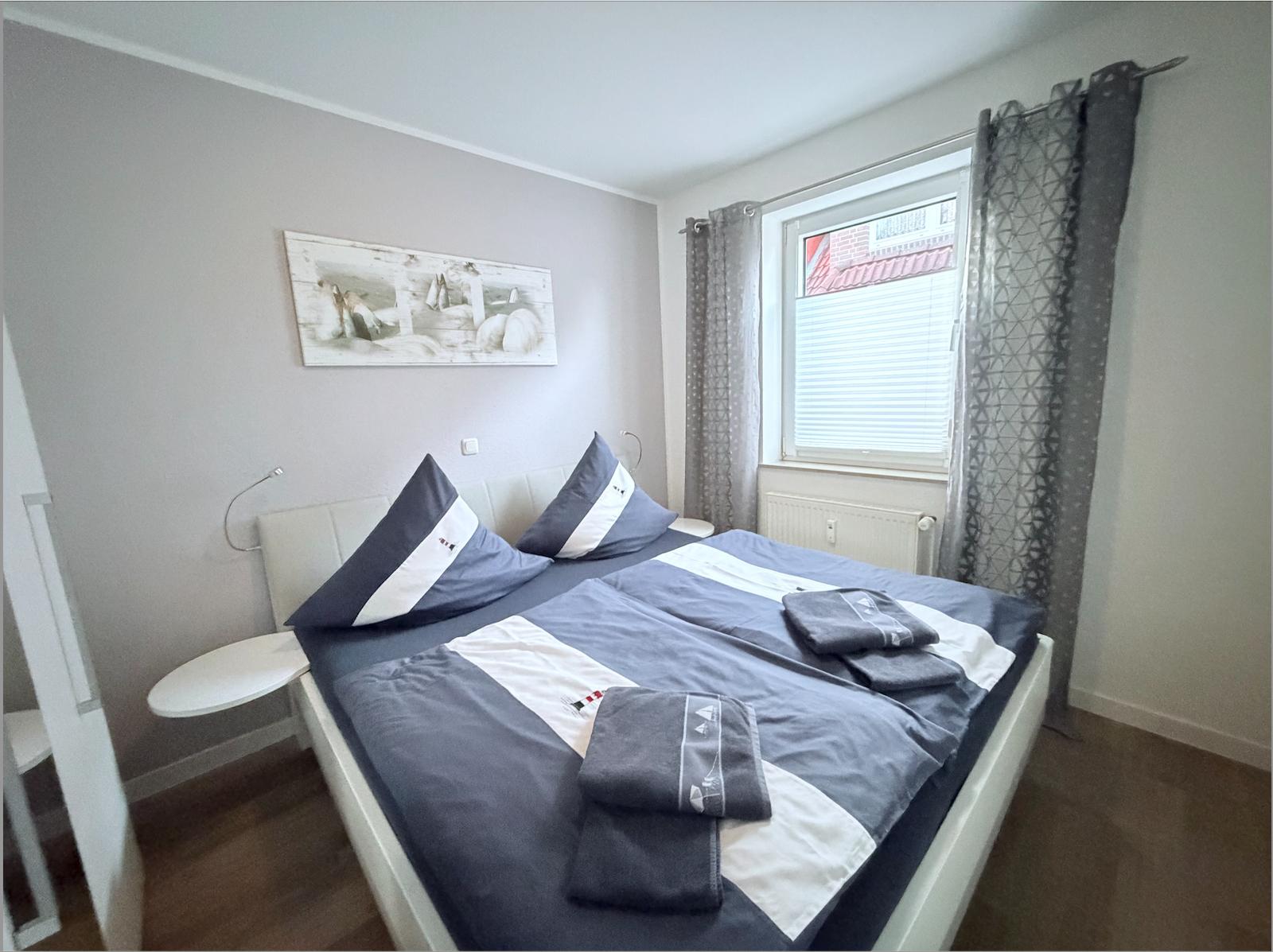 Bedroom with double bed, window, and wall art.