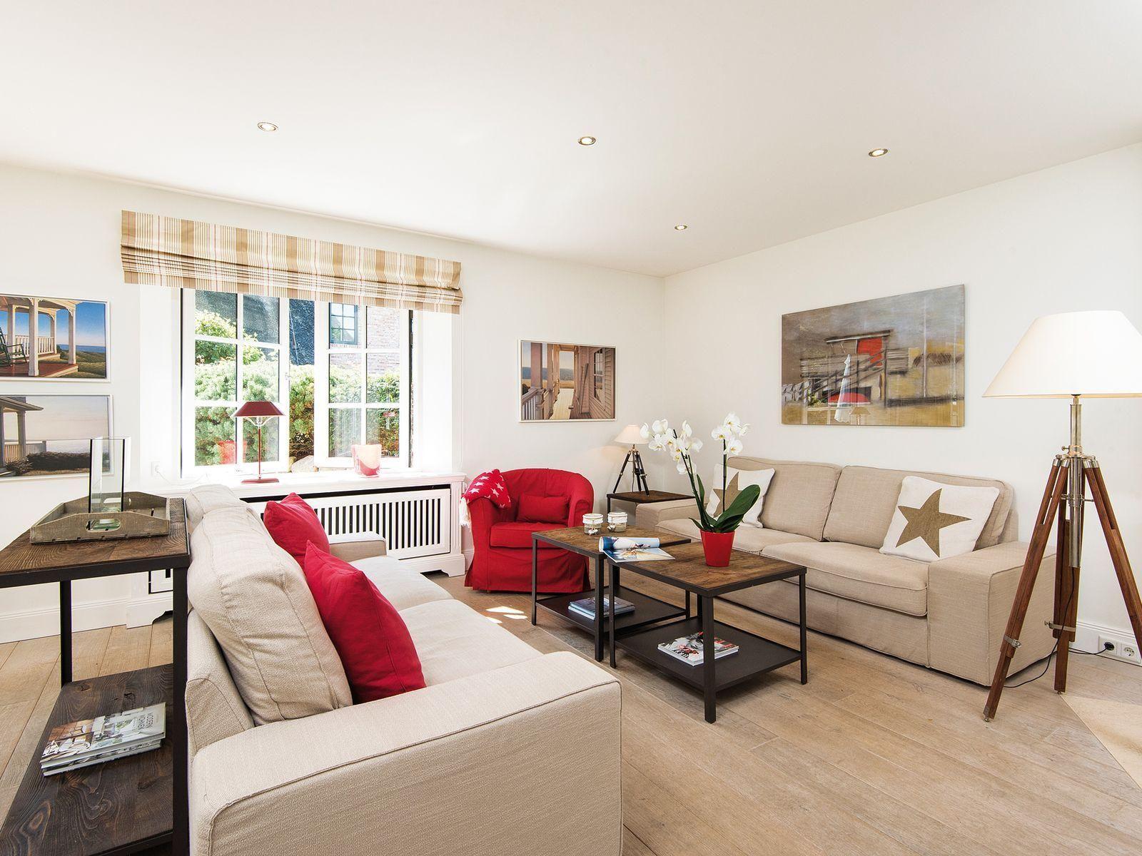 Living room with two sofas, red armchair, and wooden floor.