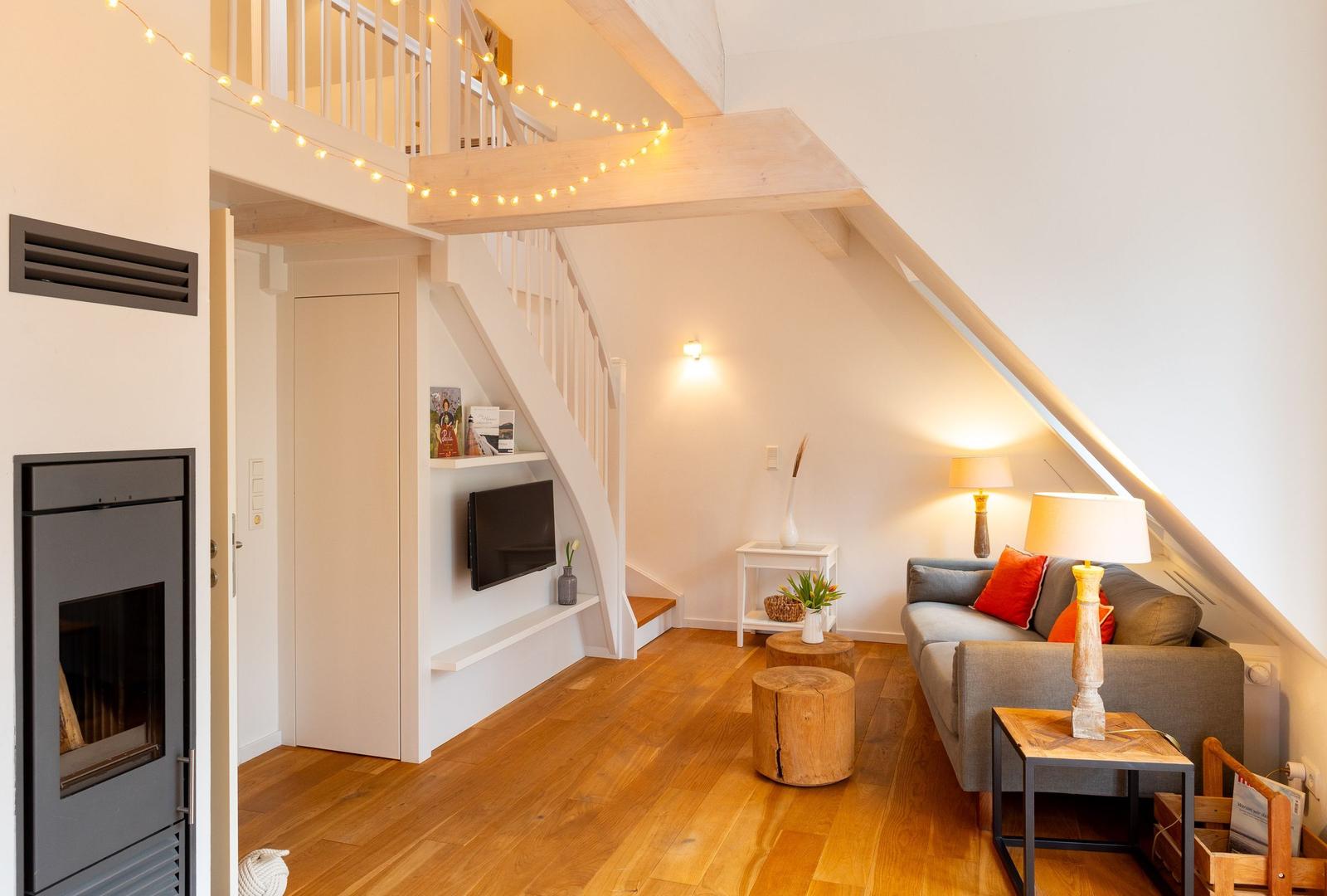 Wohnbereich mit Sofa, Fernseher und Holzboden unter Dachschrägen.