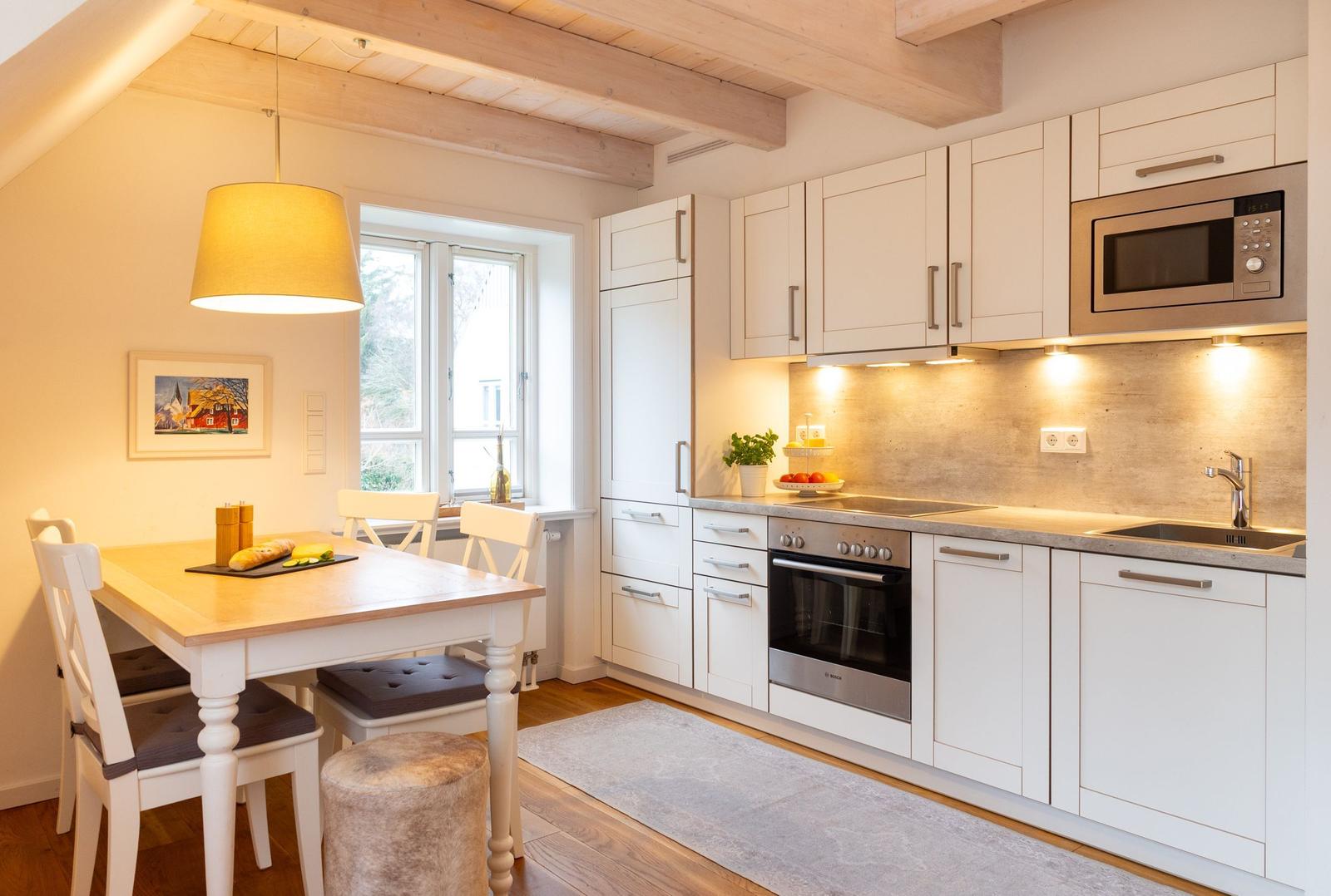 Küche mit Essbereich, weißen Schränken und Holzdecke.