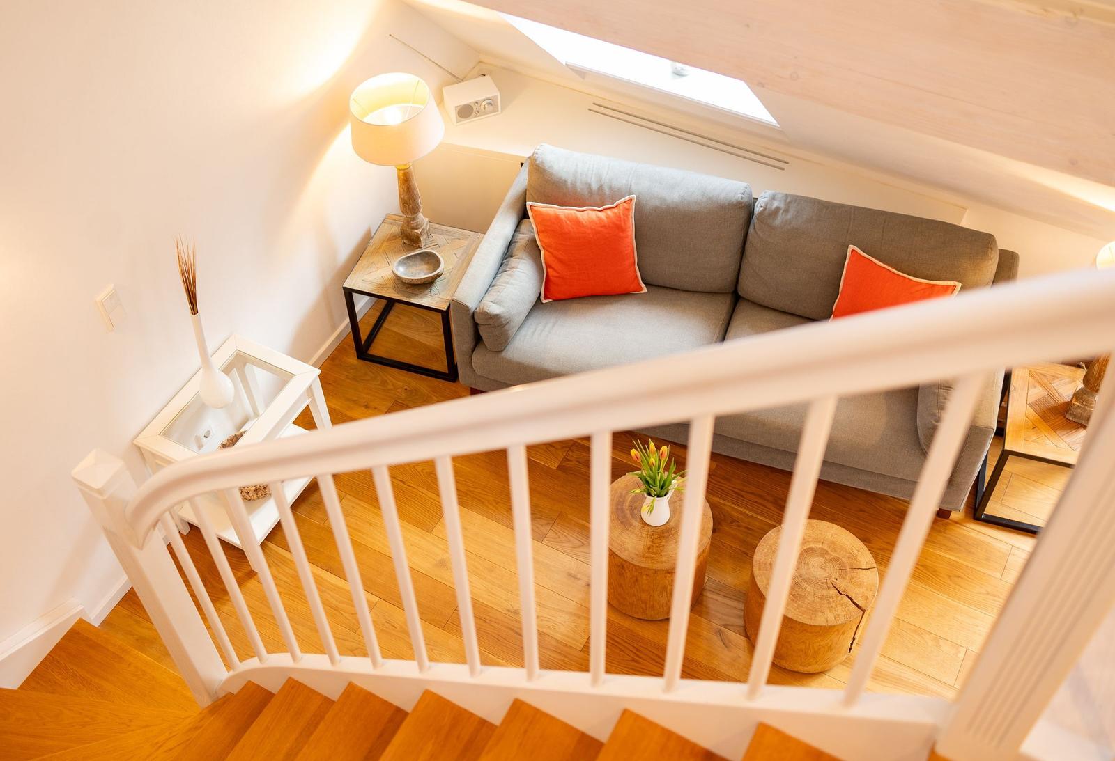 Wohnzimmer mit Sofa, Tisch und Stühlen unter Dachschrägen.