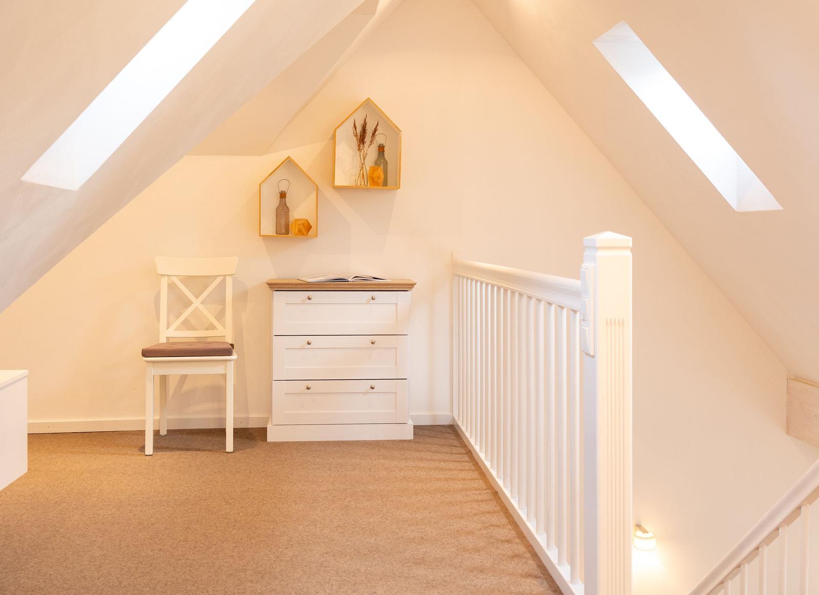 Dachgeschosszimmer mit Schrank, Stuhl und Dachschrägen.