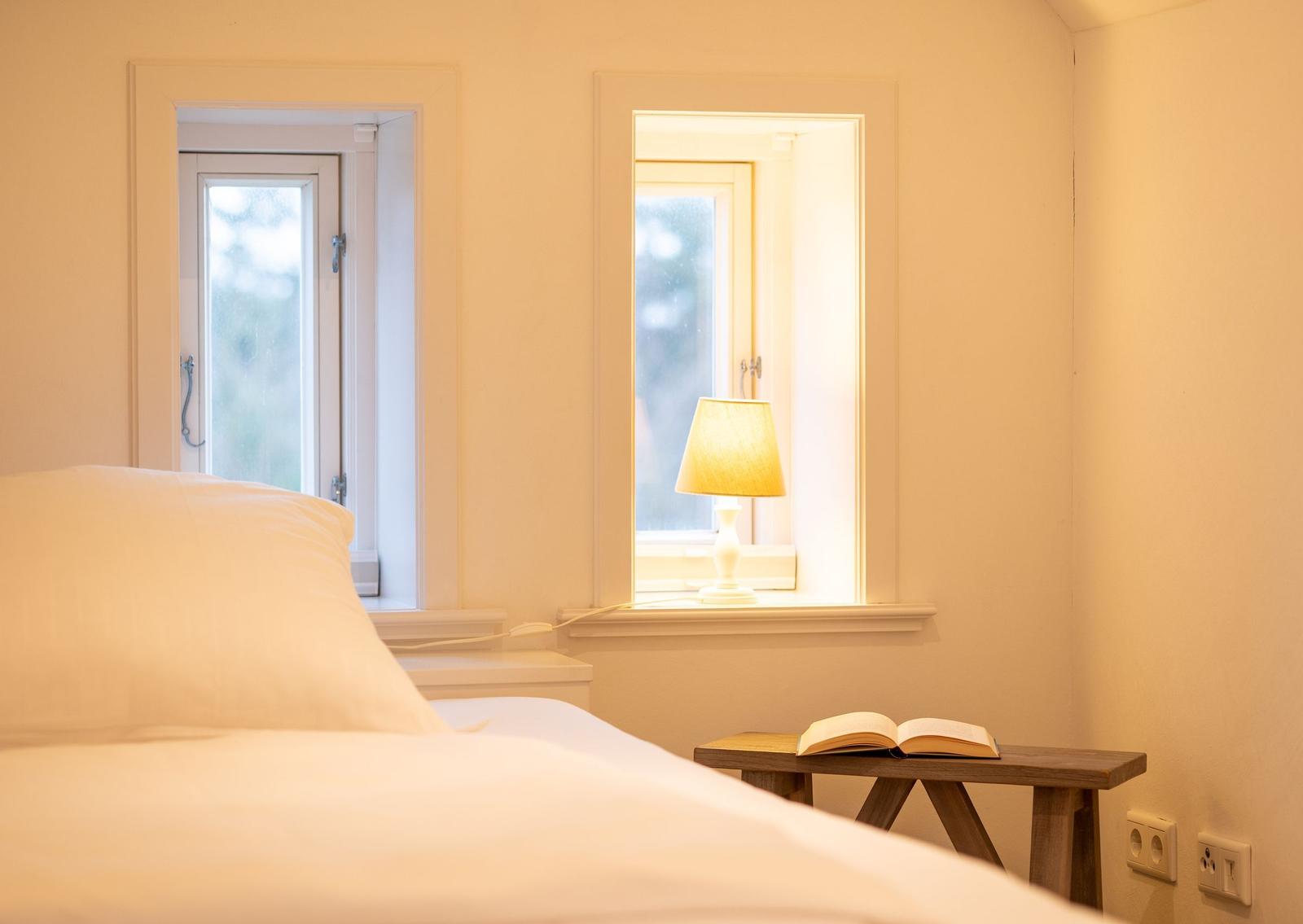 Schlafzimmer mit Bett, Tisch, Lampe und offener Tür.