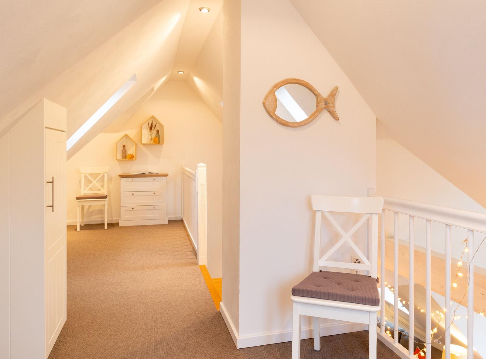 Dachgeschoss mit Stufen, Stuhl und Spiegel an der Wand.