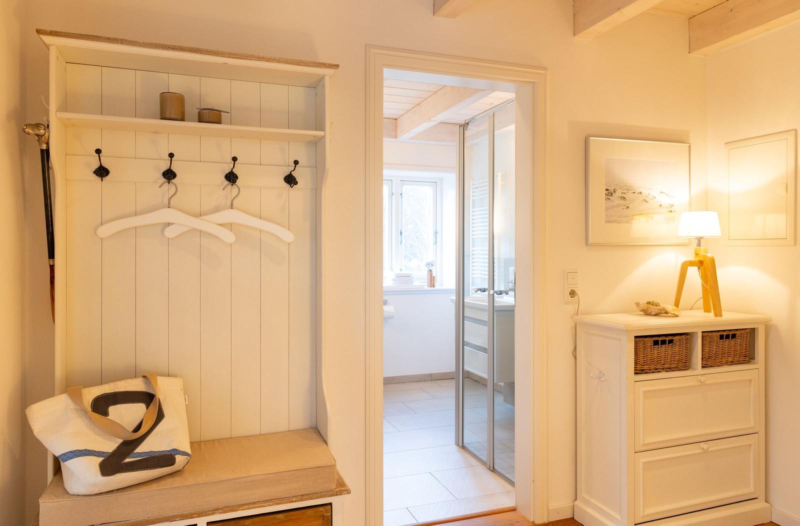 Eingangsbereich mit Garderobe, Schrank und Blick in das Bad.