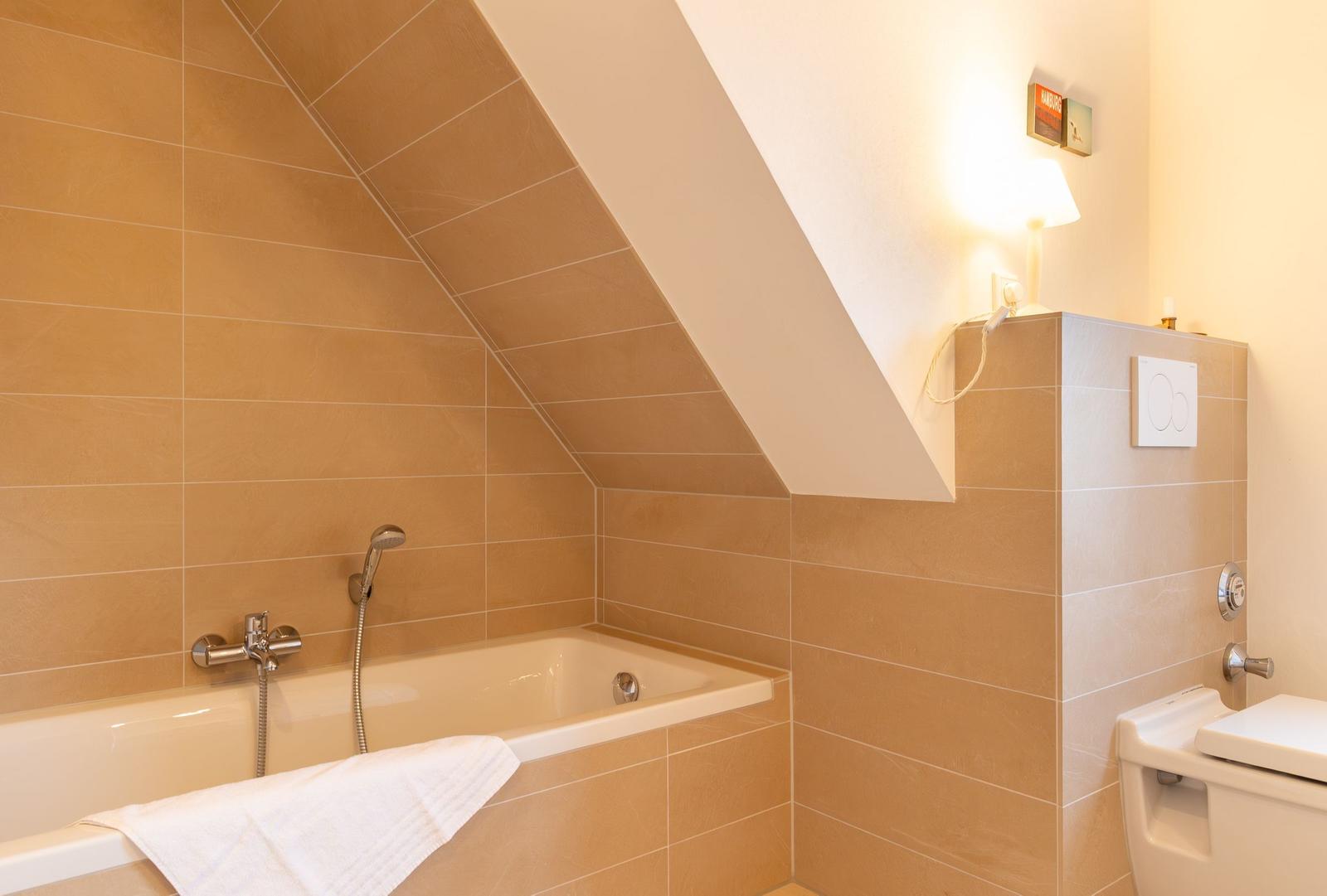 Badezimmer mit Badewanne, Toilette und Dachschrägen