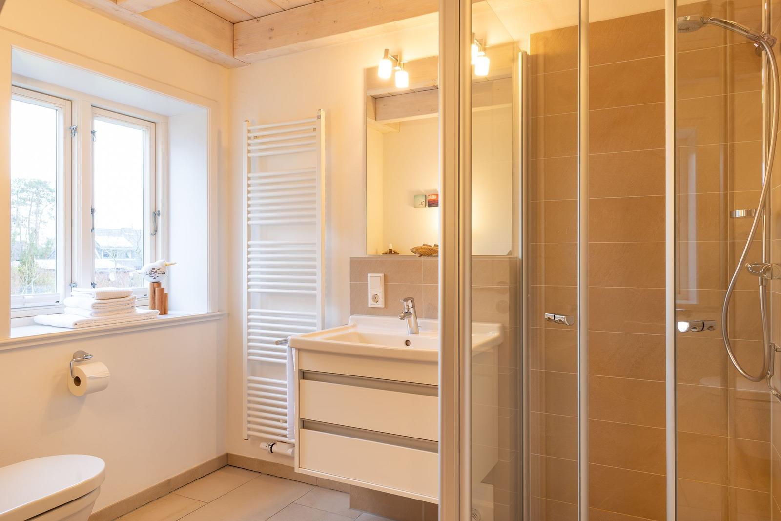 Badezimmer mit Dusche, Waschbecken und Fenster.