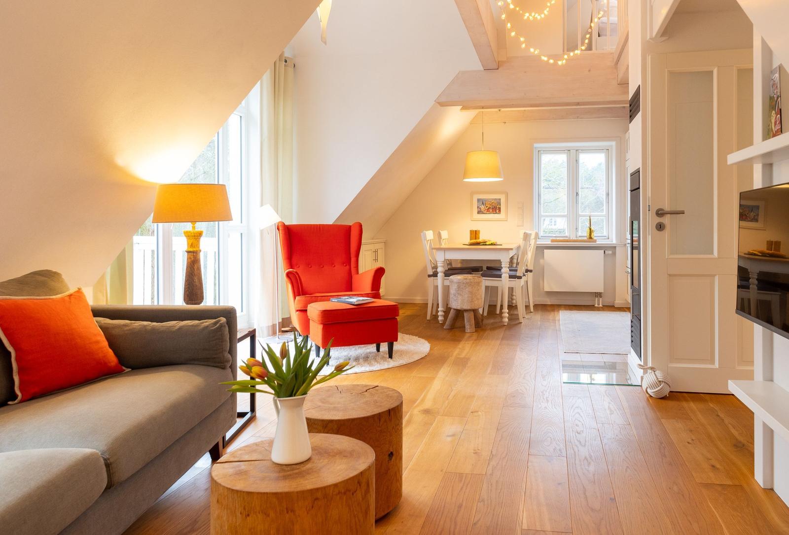 Wohn- und Essbereich mit Holzboden, rotem Sessel und Tisch mit Stühlen.