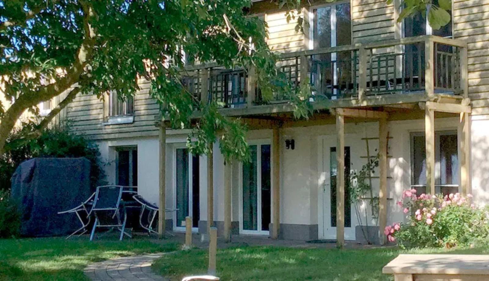 Haus mit Balkon, Garten und Terrasse. Eingangstür und Fenster sind sichtbar.