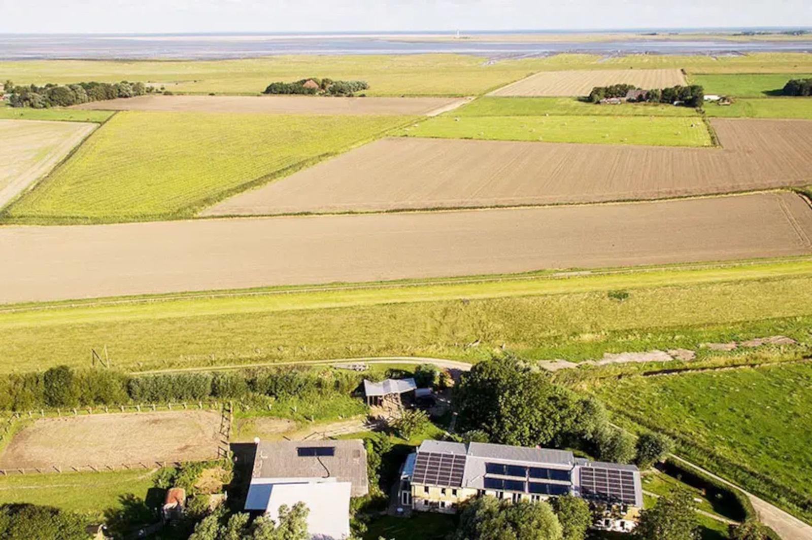 Haus mit Solaranlage in ländlicher Umgebung mit Feldern und Wasser.