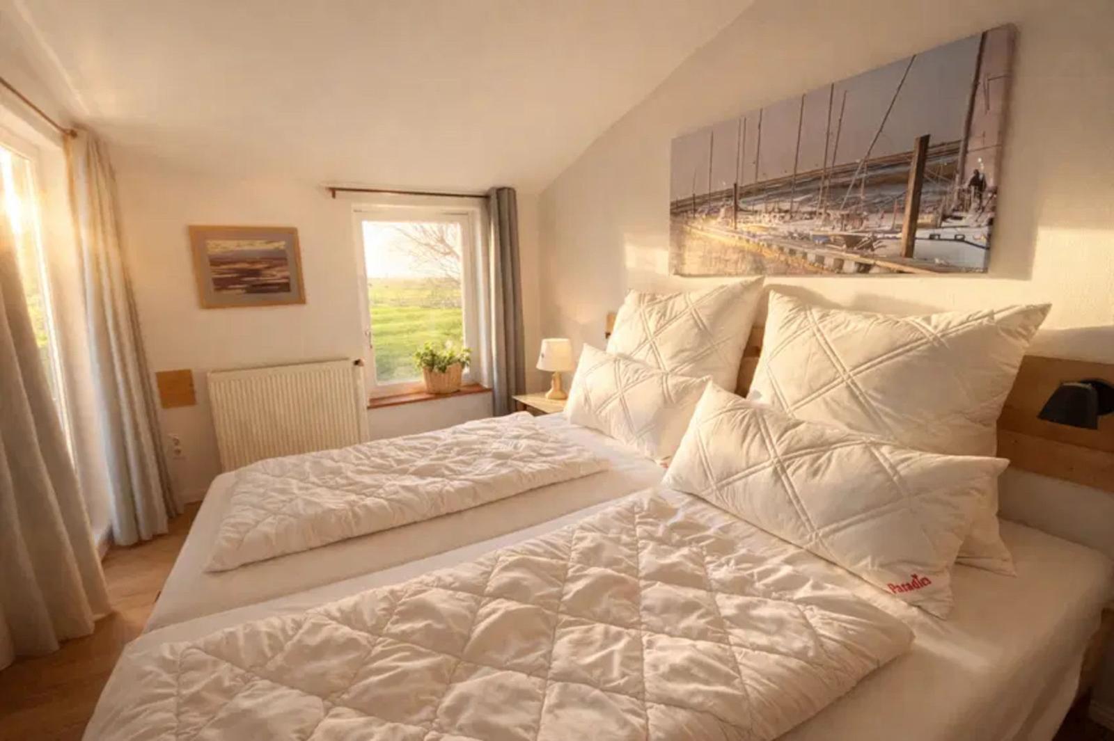 Schlafzimmer mit Doppelbett, Fenster und Wandbild.