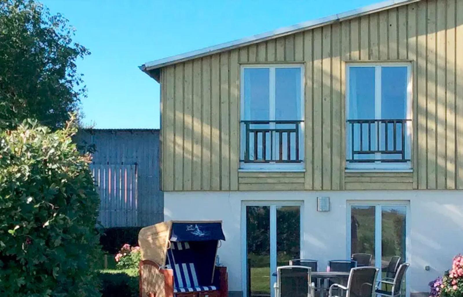 Haus mit Balkonen und Terrasse mit Gartenmöbeln und Strandkorb.