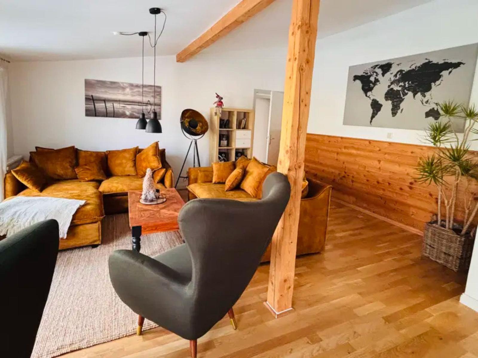 Wohnzimmer mit braunem Sofa, grauer Sessel und Holzboden.