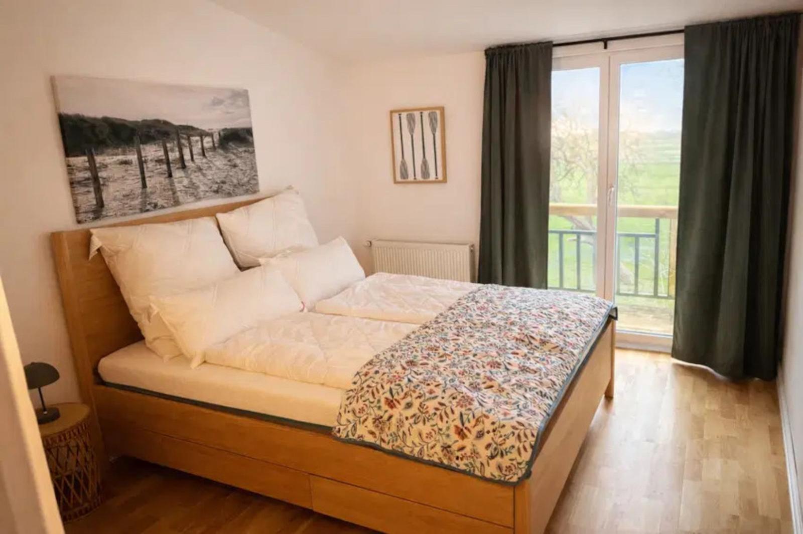 Schlafzimmer mit Doppelbett, Balkon und Holzboden.